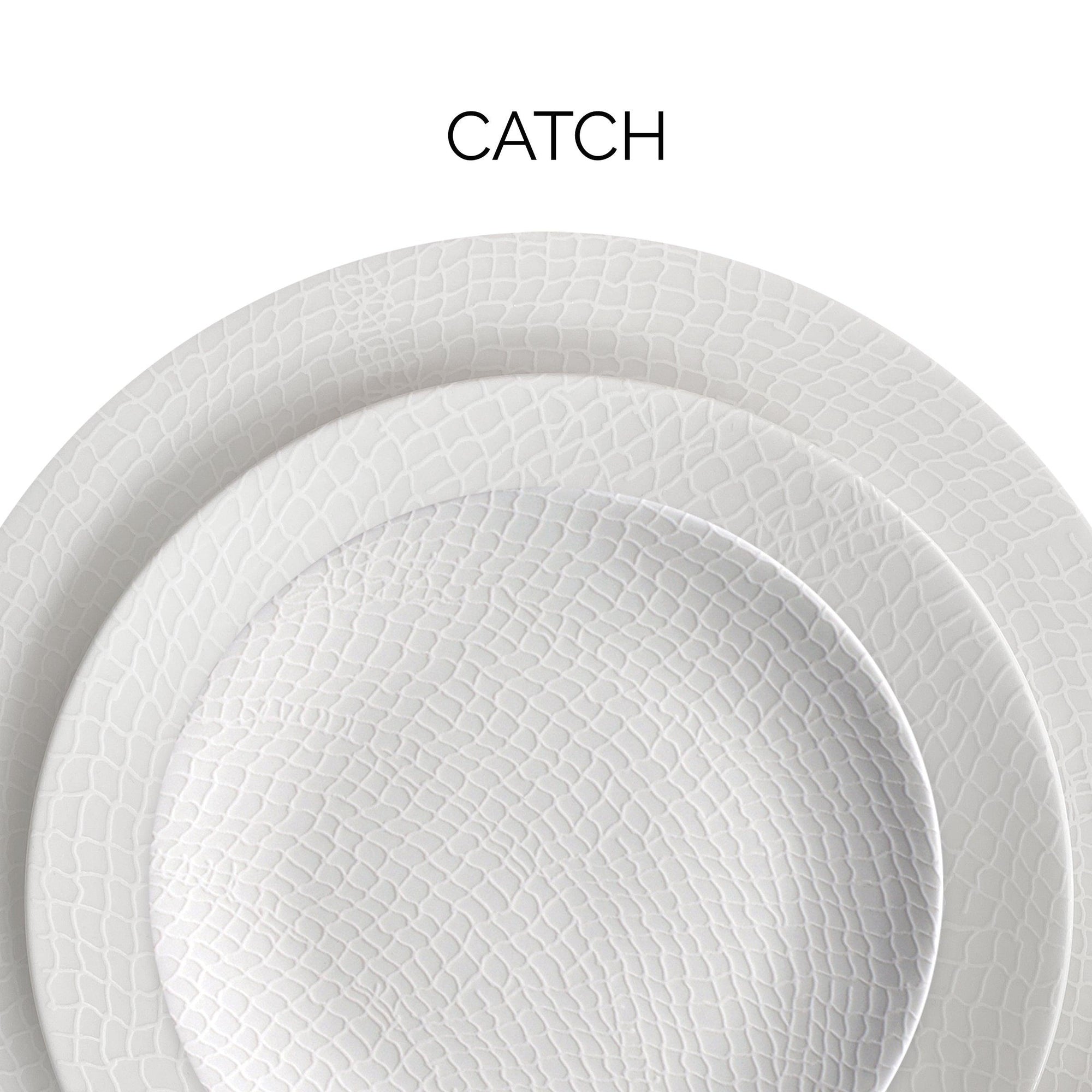 Close-up of two stacked textured white plates with the word "CATCH" above them.