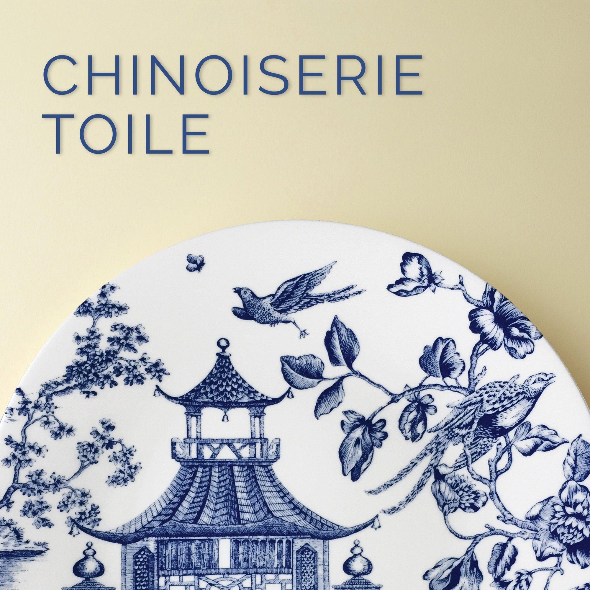 A round plate with blue Chinoiserie toile design featuring a pagoda, birds, and floral motifs against a light background. Text reads "Chinoiserie Toile.