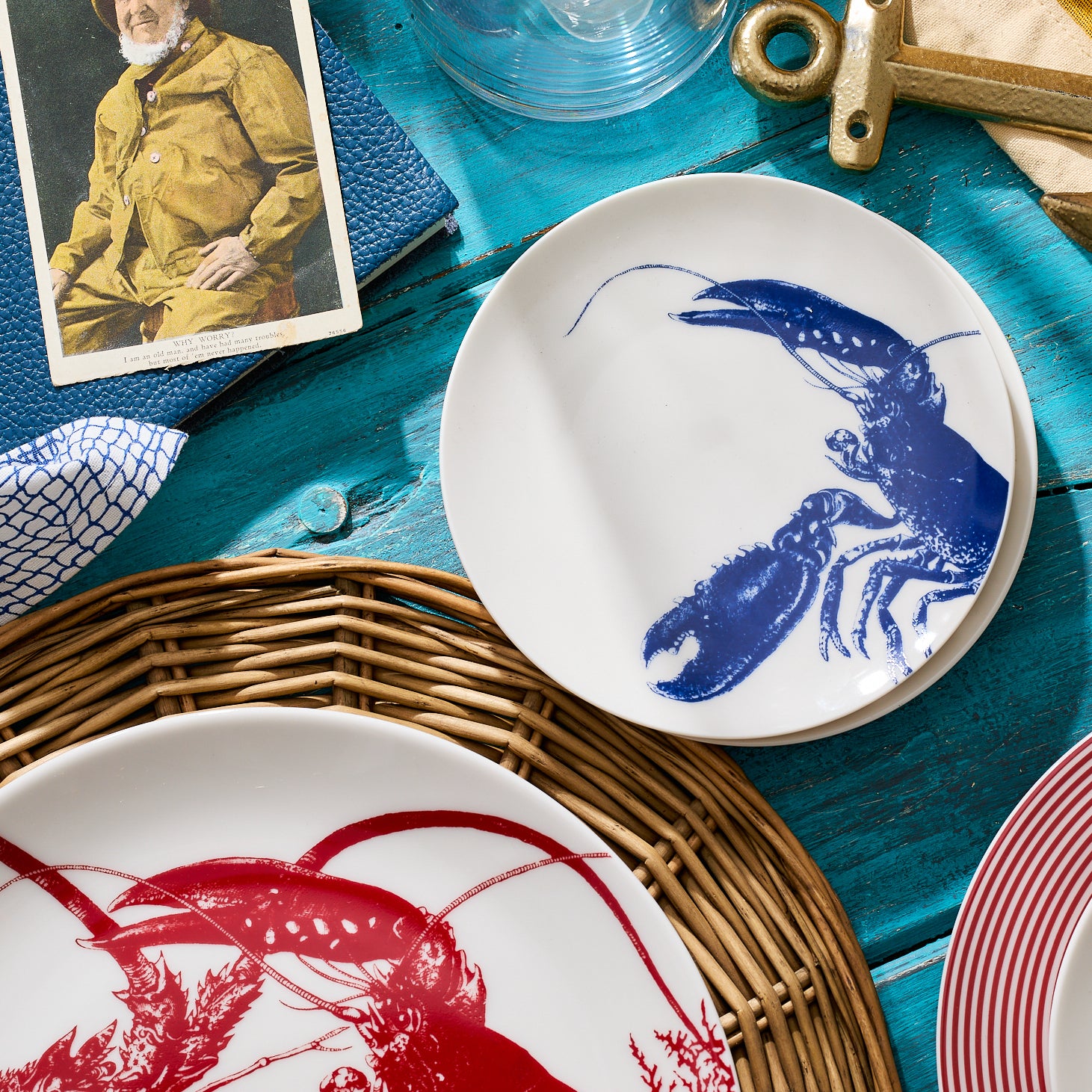 Four white heirloom-quality dinnerware plates each feature a blue lobster illustrated in the center. These Lobster Small Plates by Caskata Artisanal Home overlap slightly, beautifully displaying the entire lobster design, reminiscent of New England's coast.
