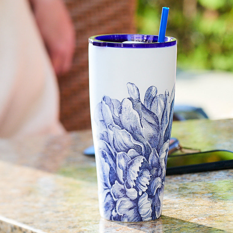 The Peony Stainless Steel Insulated Tumbler by Caskata features a blue floral design with a matching blue straw on a white base, combining style and functionality. Its stainless steel construction ensures your drink remains at the ideal temperature for an extended period.