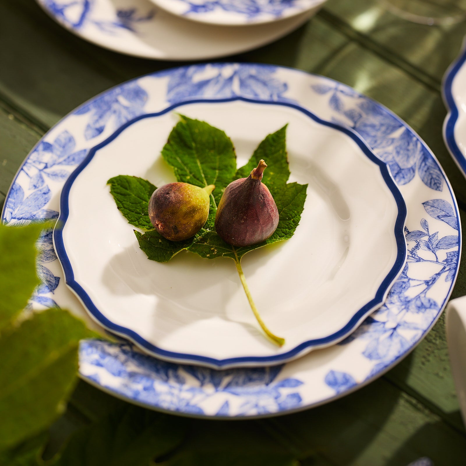 A top-view of the Stella Scalloped Blue Salad Plate by Caskata, featuring white porcelain with a scalloped edge and dark blue trim, evokes the charm of vintage dinnerware.