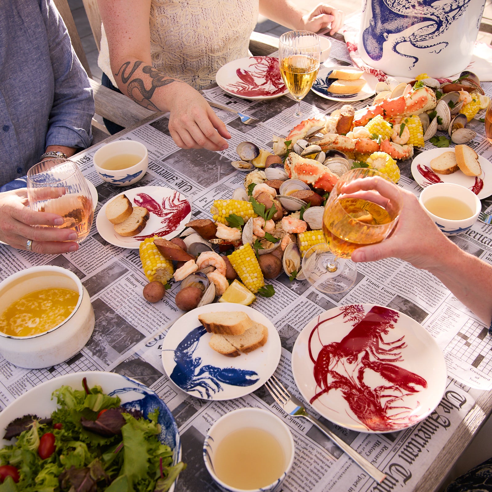 A white Caskata Lobster Coupe Salad Plate featuring a red illustration of two lobsters and some seaweed, crafted from premium porcelain to add a touch of seaside style.