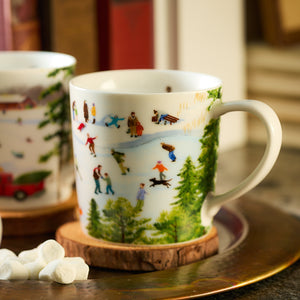 A porcelain mug from the Caskata X Felix Doolittle Winter Wonderland Mugs collection, set of 4, featuring a vibrant New England winter scene with people ice skating and playing in the snow, elegantly placed on a wooden coaster.