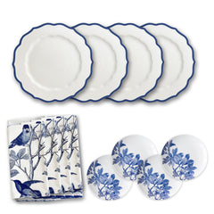 The Blue Branches Luncheon Bundle by Caskata, part of the Stella collection, includes four white plates with blue trim, five smaller plates with a blue leaf design, and a bird-and-tree patterned napkin—perfect for hosting gatherings or enhancing your spring table décor.