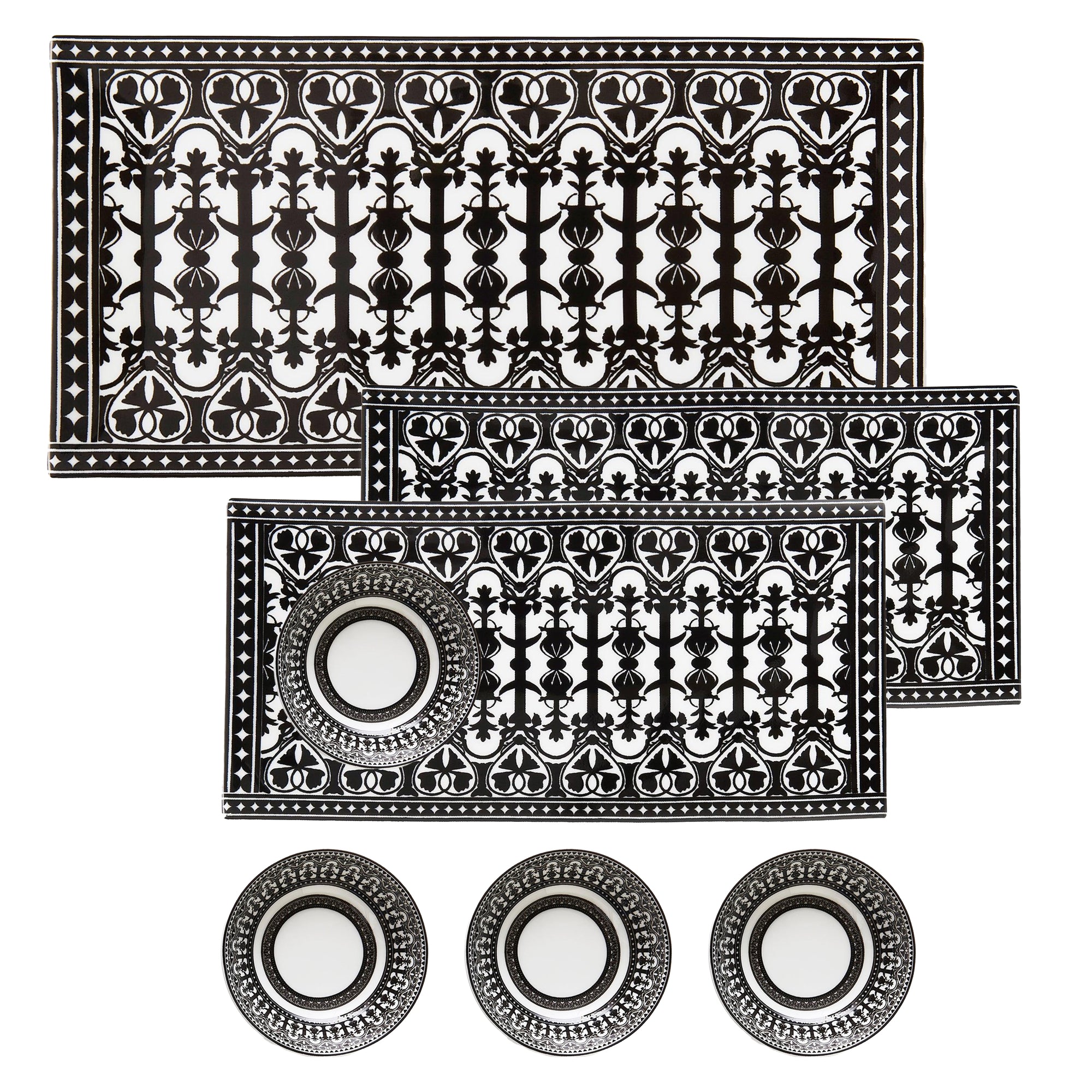 The Casablanca Serving Bundle by Caskata includes a black-and-white patterned bone china set with two rectangular serving trays for appetizers and four round coasters, all featuring intricate geometric designs.