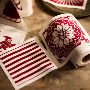 A closeup of deep red and white cocktail napkins made of 100% cotton, 50 on a roll in mixed holiday patterns from Caskata