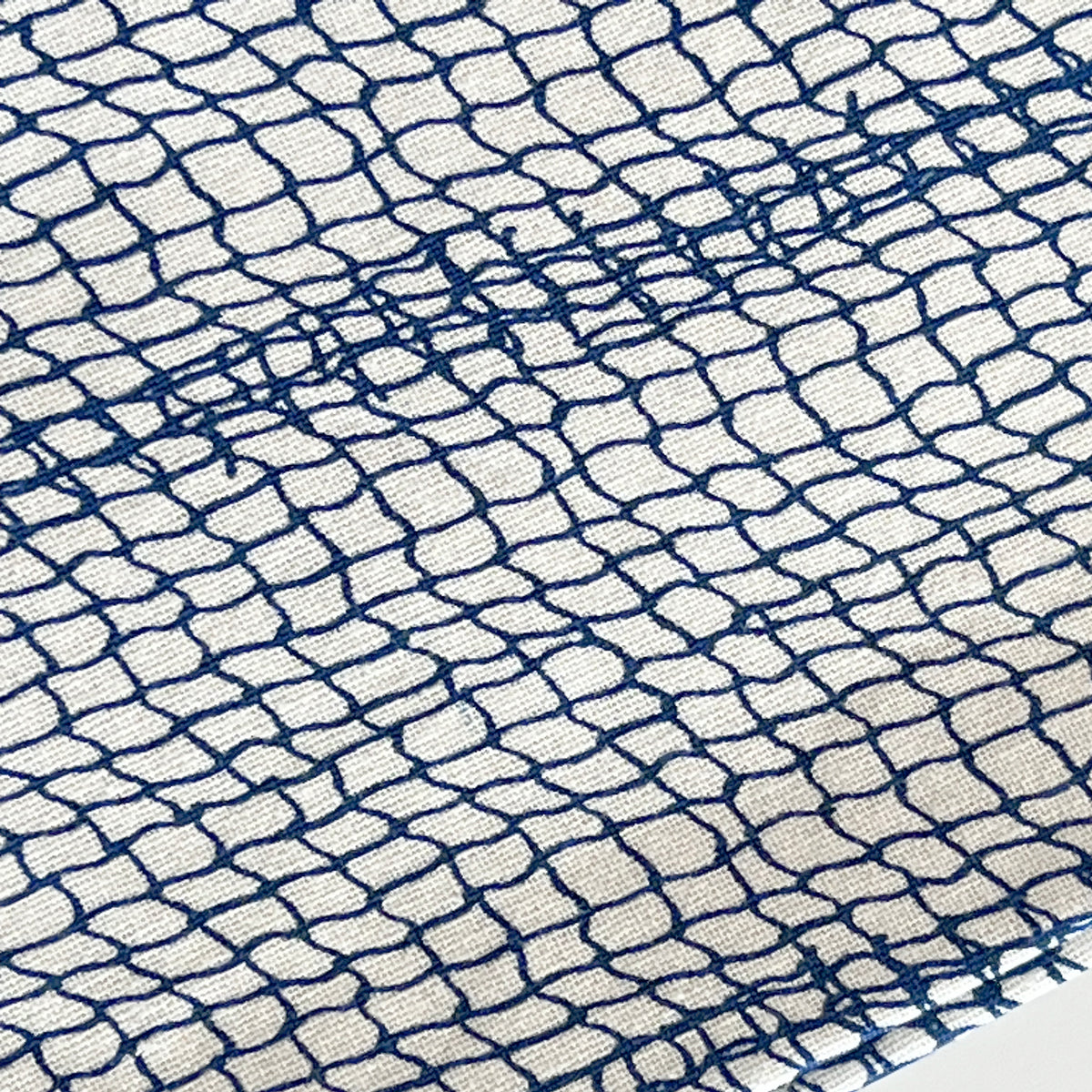 Close-up of a white fabric with an irregular blue grid pattern, reminiscent of rippling water at a serene lake house from the Lake House Bundle by Caskata.
