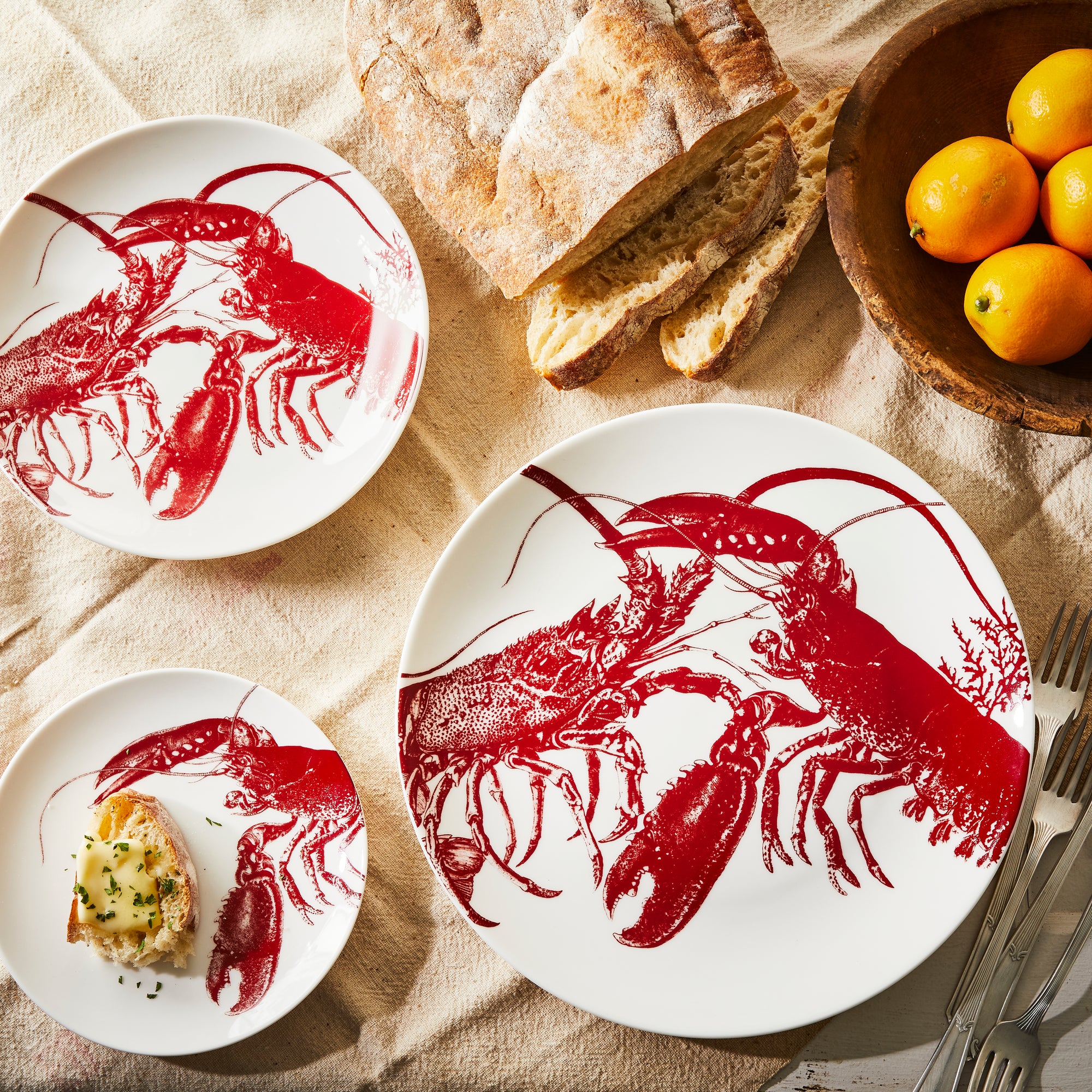 A set of Caskata Beach Wedding Bundle plates featuring red lobster designs, arranged in groups of various sizes.
