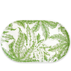 The Freya Large Coupe Oval Platter by Caskata features a stunning green botanical leaf pattern on a white porcelain background, making it an essential piece for entertaining.