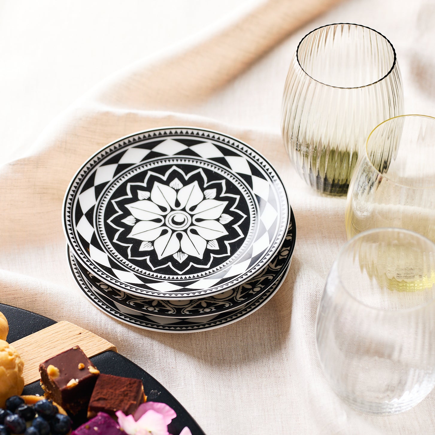 Four black and white decorative round Fez Small Plates by Caskata Artisanal Home, featuring bold geometrics and a Moroccan pattern, arranged with overlapping edges against a white background.