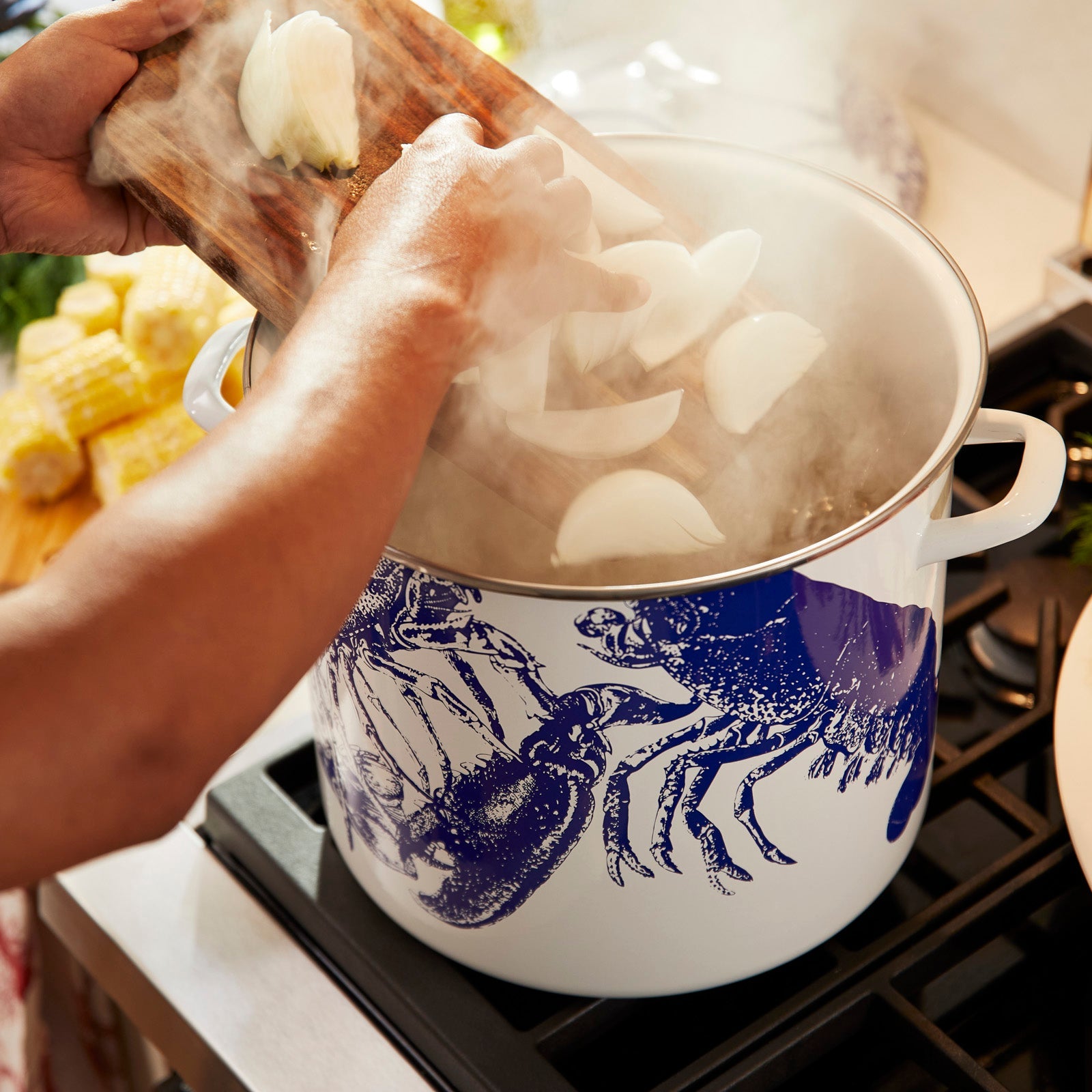 A white kitchen pot with blue lobster designs, paired with blue and white Blue Lobsters Dinner Napkins and six white Crab Entrée Bowls featuring similar motifs, the Lobster Boil Bundle by Caskata.