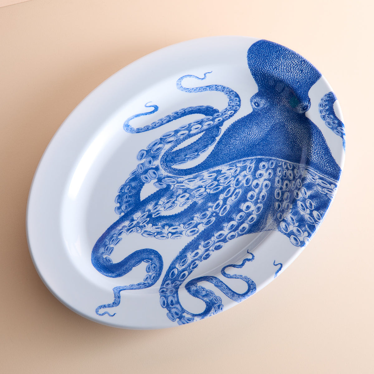 Caskata&#39;s Lucy Melamine Oval Rimmed Platter showcases a detailed blue octopus design on a beige background.