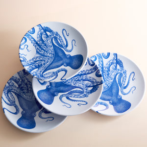 The Lucy Melamine Dinner Plates by Caskata, featuring intricate blue designs, elegantly overlap on a light surface, bringing marine magic to the table setting. This set of four plates adds a touch of seaside charm to any dining experience.