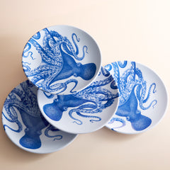 The Lucy Melamine Dinner Plates by Caskata, featuring intricate blue designs, elegantly overlap on a light surface, bringing marine magic to the table setting. This set of four plates adds a touch of seaside charm to any dining experience.