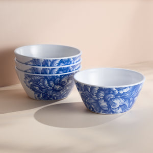 A set of four Caskata Peony Melamine Cereal Bowls with blue floral patterns is stacked beside one similar bowl, highlighting their elegant design.