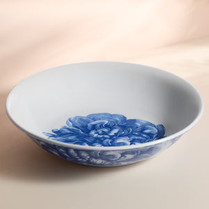 The Caskata Peony Melamine Serving Bowl showcases a graceful blue peony design on white, beautifully presented on a neutral background.