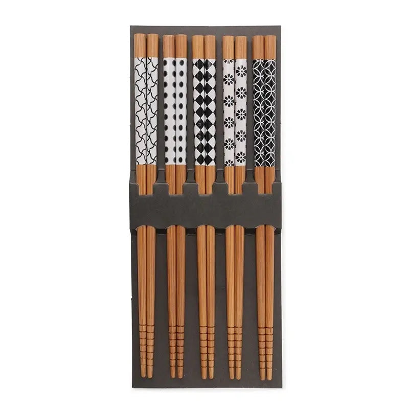 The Nara Chopsticks by Miya, Inc. is a set of five pairs of bamboo chopsticks featuring various black and white patterns on the handles, displayed vertically in a gray holder—perfect for complementing sushi trays or entrée bowls.