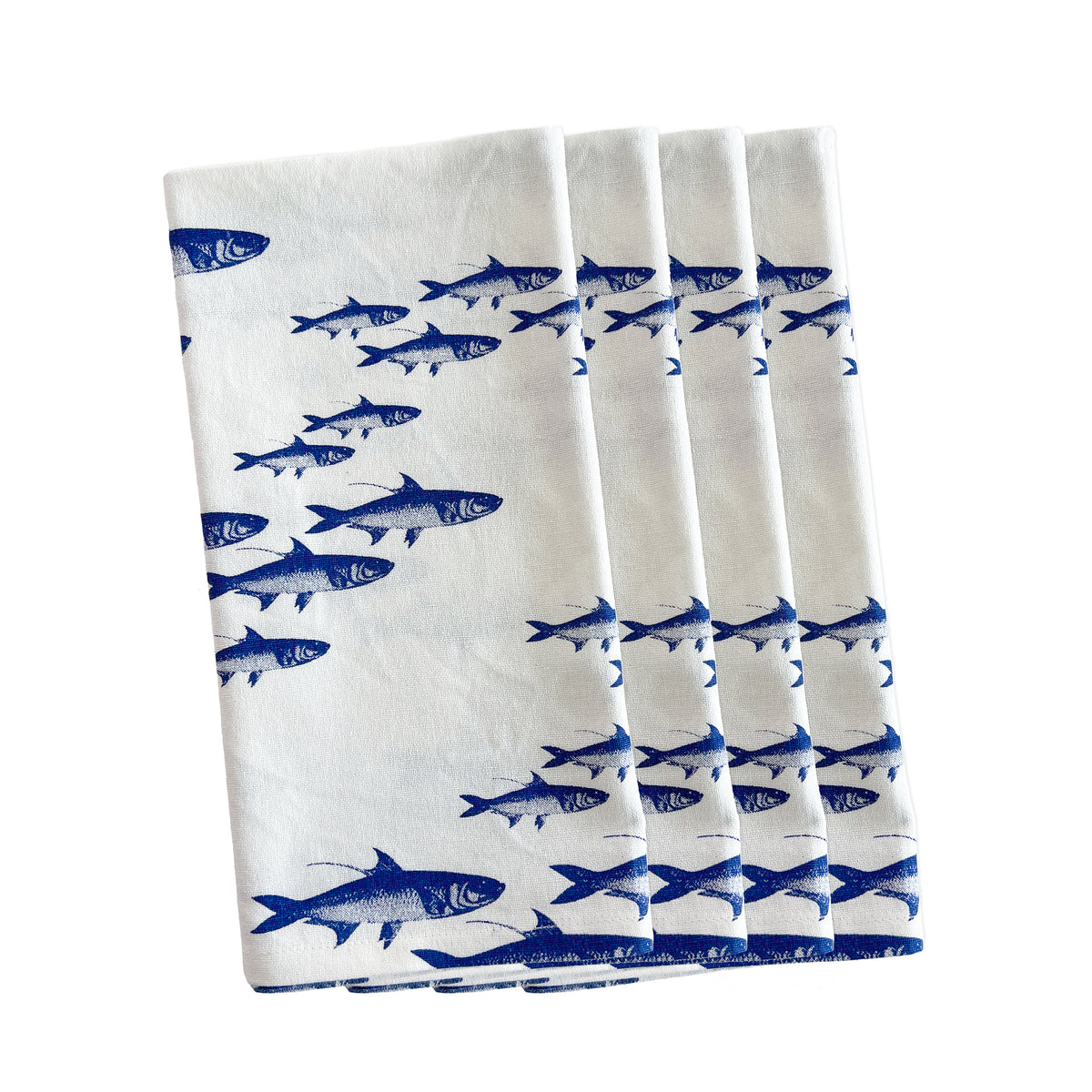 From Caskata&#39;s High Tide Essentials Bundle, four white towels featuring blue fish prints are elegantly stacked.