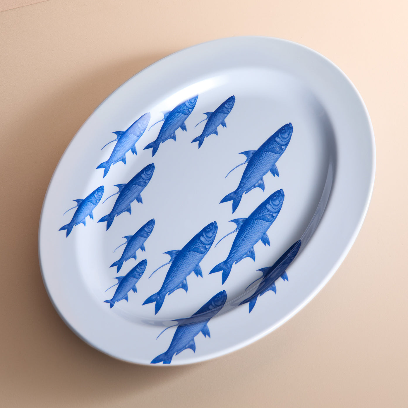 The Caskata School of Fish Melamine Oval Rimmed Platter, featuring blue fish illustrations in a clockwise pattern, adds a coastal vibe to your table. Made from BPA-free melamine, it blends style and functionality perfectly.