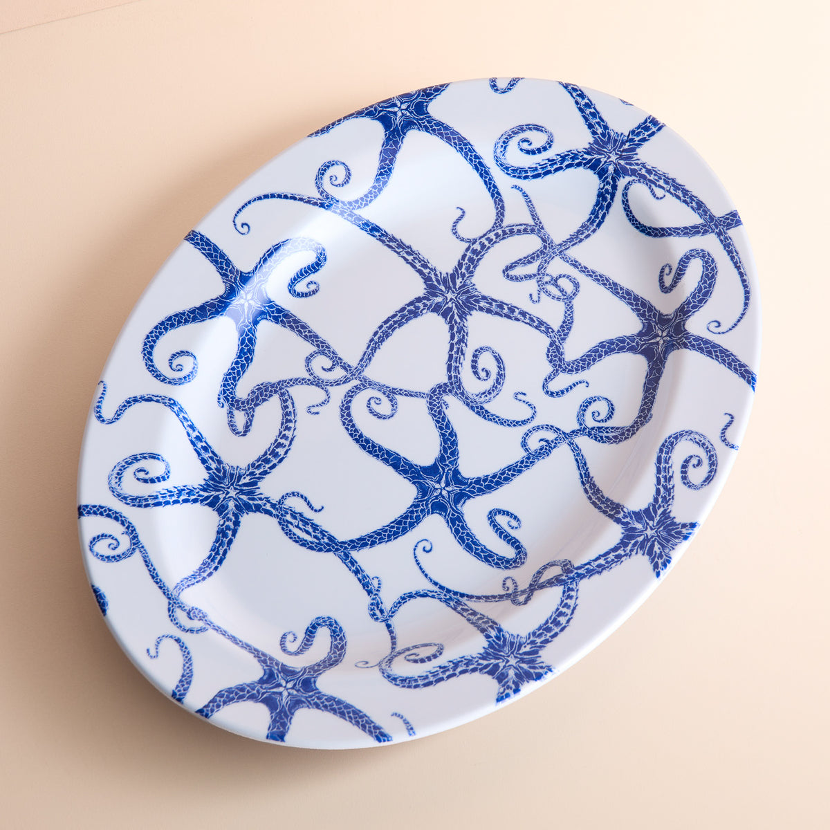 Starfish Melamine Oval Rimmed Platter by Caskata: A BPA-free white plate adorned with a charming blue octopus design.