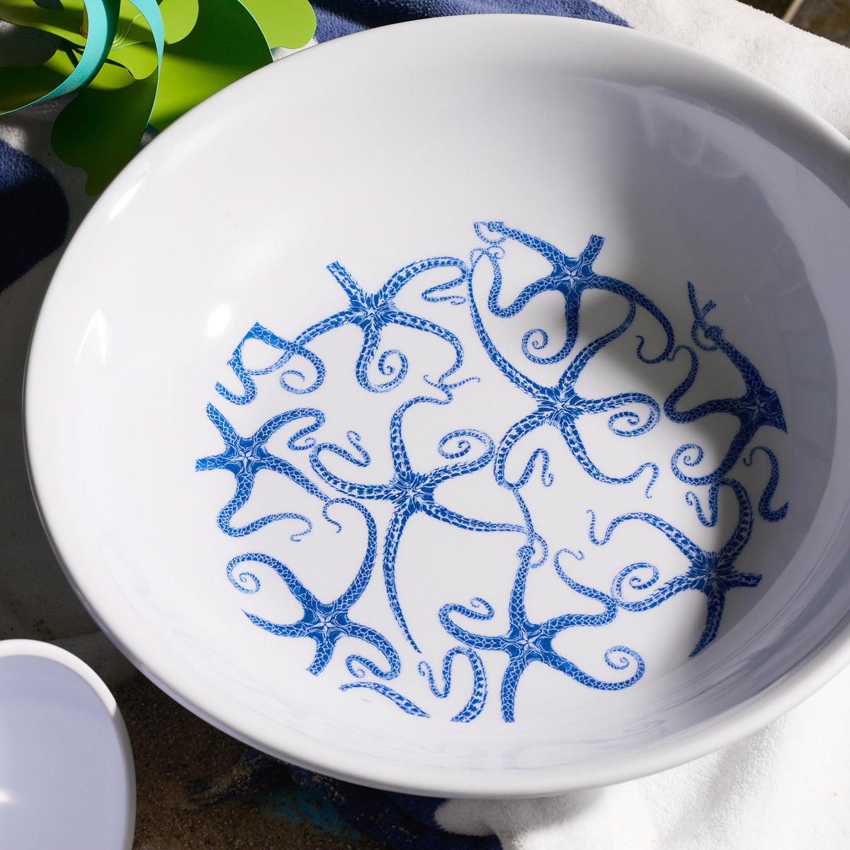 The Caskata School of Fish Melamine Serving Bowl, featuring a seaside vibe with its blue starfish pattern on white, is perfect for outdoor entertaining. Its BPA-free melamine construction ensures durability for any gathering.